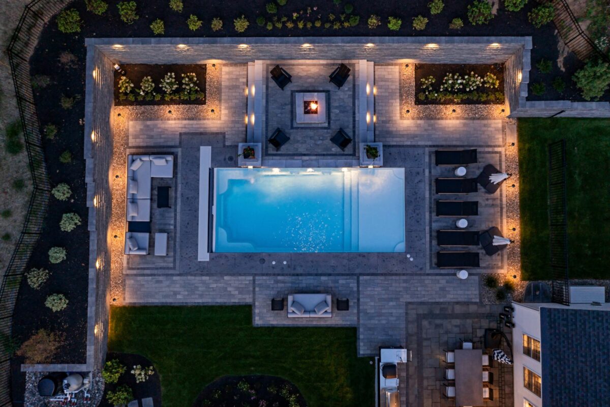 Aerial view of a patio with pool, lighting, and fire pit